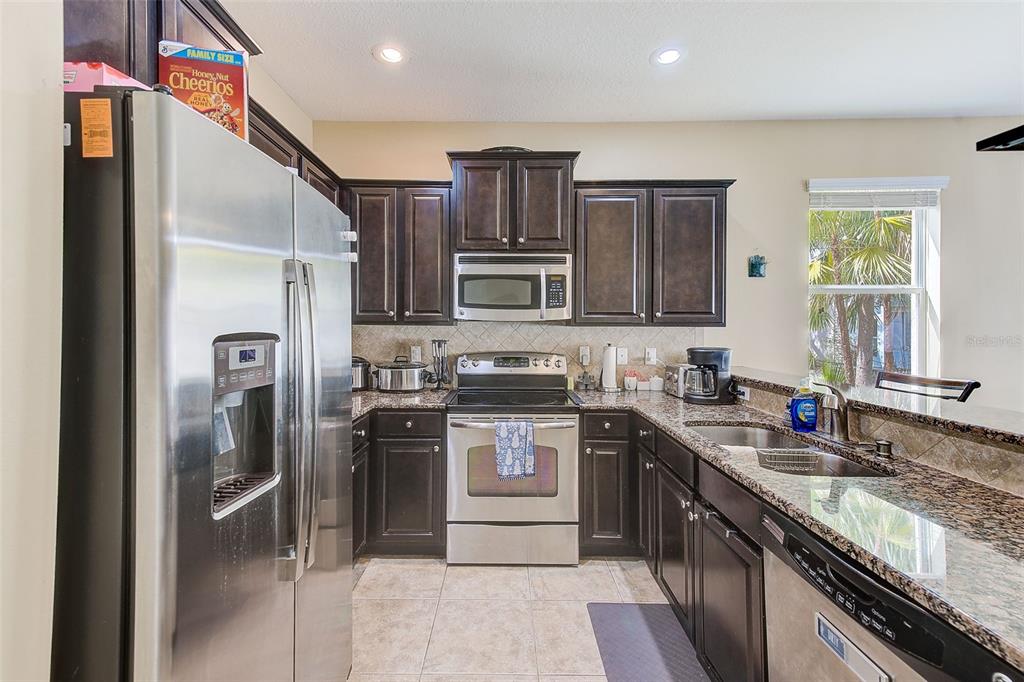 780 Spring Flowers Trail Brandon, FL 33511 - Photo 9 of 33 a kitchen with stainless steel appliances granite countertop a refrigerator stove and sink