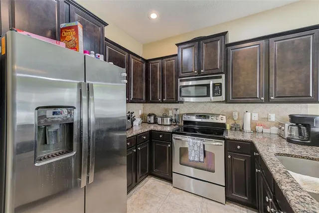 a kitchen with granite countertop a refrigerator and cabinets