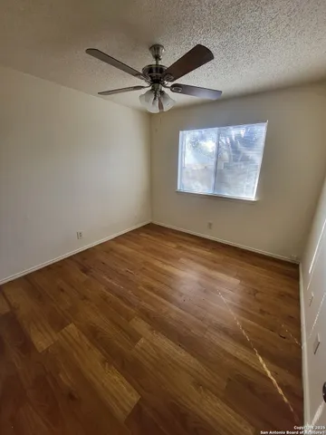 an empty room with wooden floor fan and windows