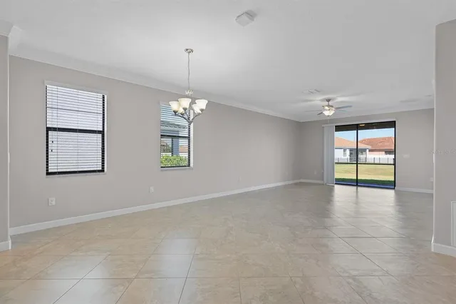 a view of an empty room with window and chandelier fan