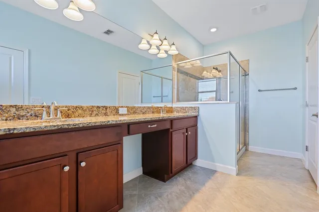 a bathroom with a granite countertop sink a large mirror and a shower
