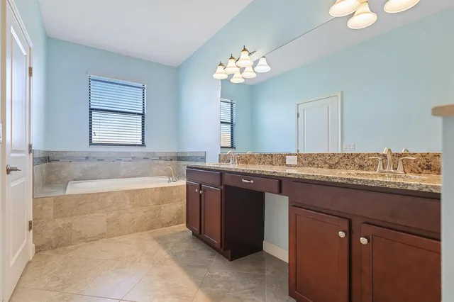 a bathroom with a granite countertop bathtub a sink and a large mirror