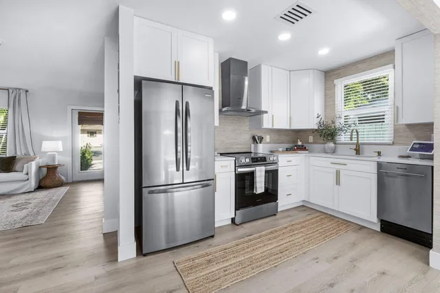 a kitchen with cabinets stainless steel appliances a sink and a window