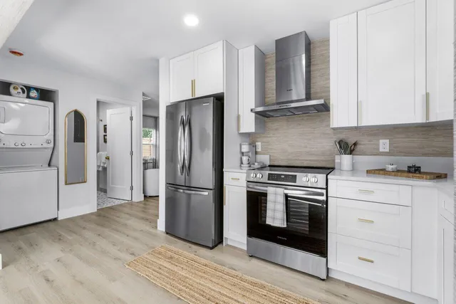 a kitchen with stainless steel appliances granite countertop a refrigerator stove and white cabinets