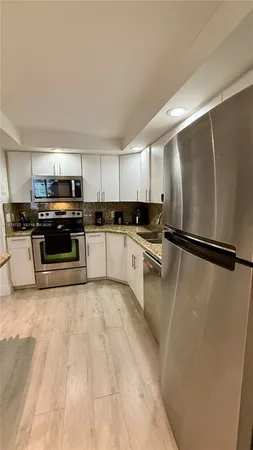 a kitchen with granite countertop a refrigerator a sink a stove a microwave and cabinets
