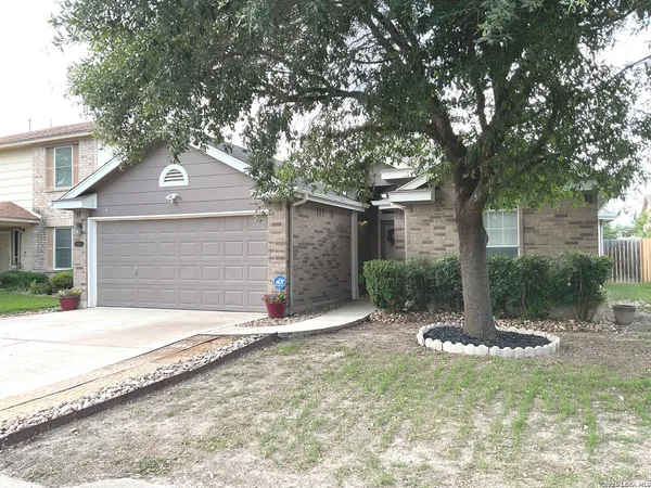 a front view of a house with a tree