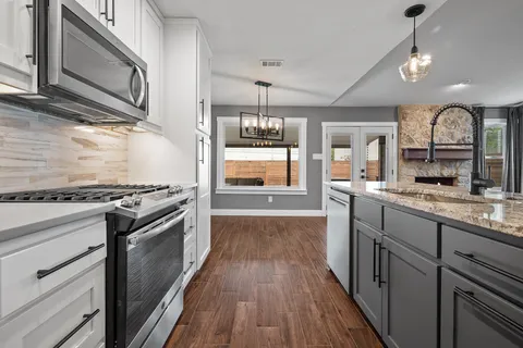 a kitchen with stainless steel appliances granite countertop a refrigerator a stove and a sink