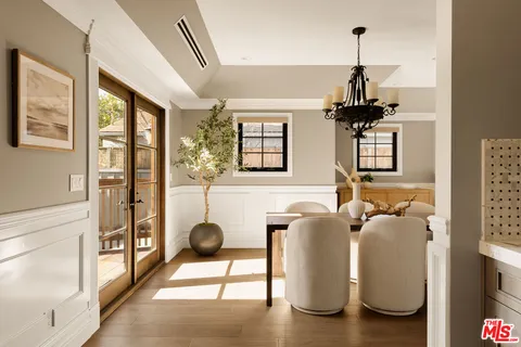 a kitchen with stainless steel appliances granite countertop a refrigerator a sink dishwasher a stove and a dining table with wooden floor