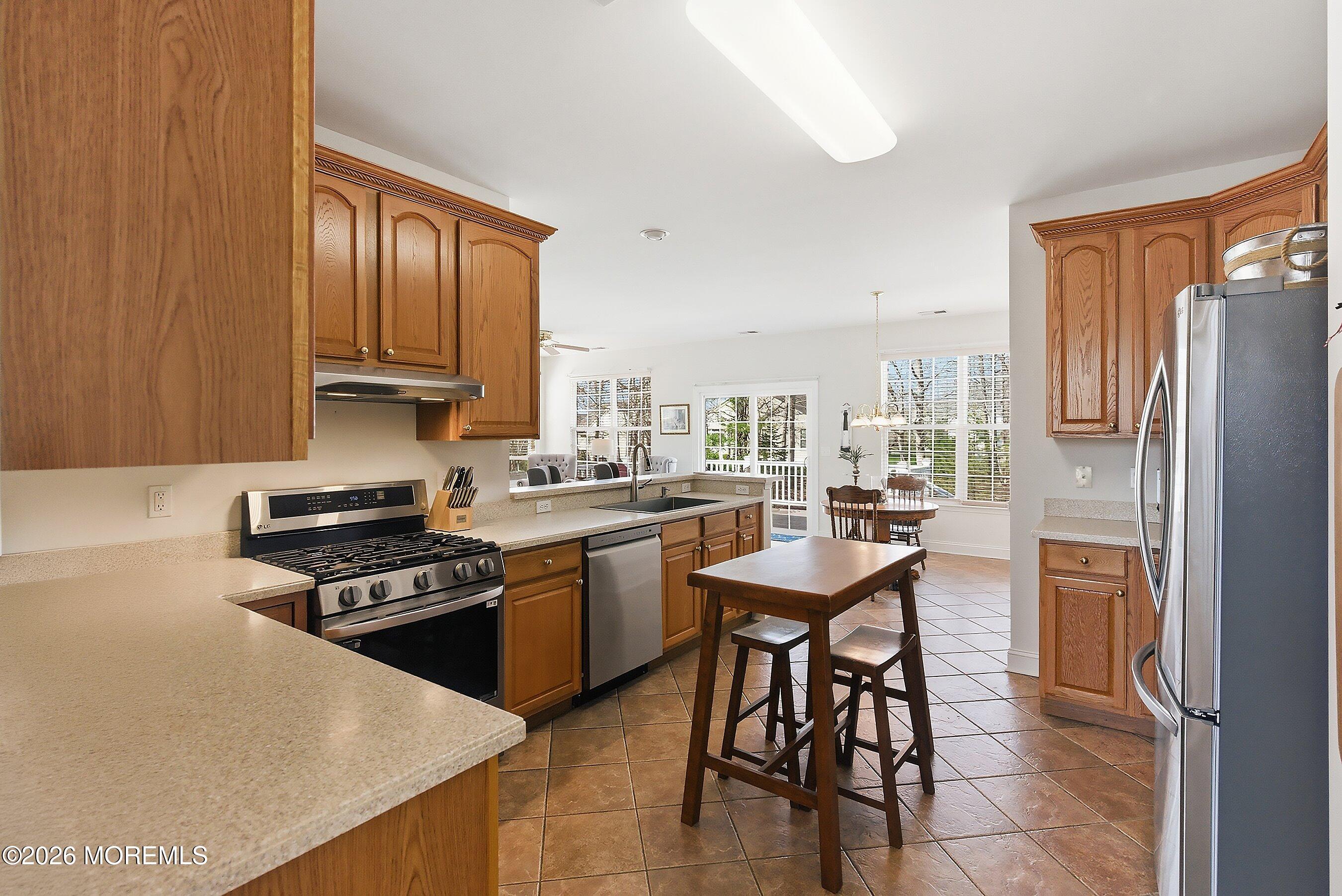 65 Mission Way Barnegat, NJ 08005 - Photo 12 of 51 a kitchen with stainless steel appliances granite countertop a stove a refrigerator a sink a dining table and chairs with wooden floor