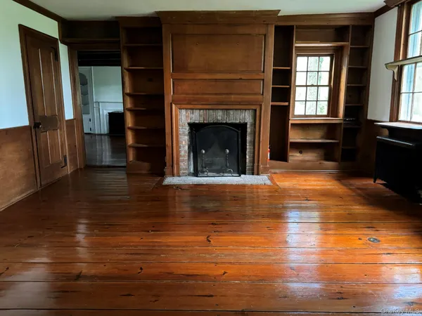a view of a livingroom with a fireplace window and wooden floor