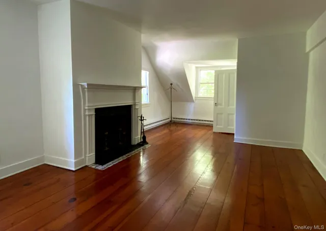 a view of an empty room with wooden floor and a fireplace