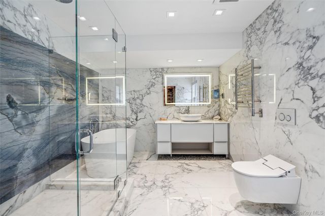 a spacious bathroom with a bathtub shower sink mirror and toilet