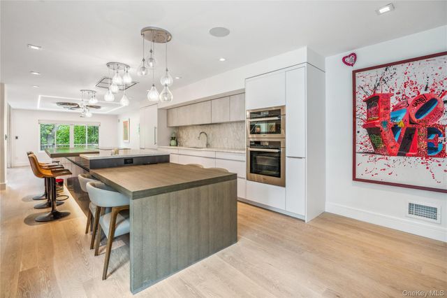 a kitchen with kitchen island a stove a refrigerator a sink and a dining table with wooden floor