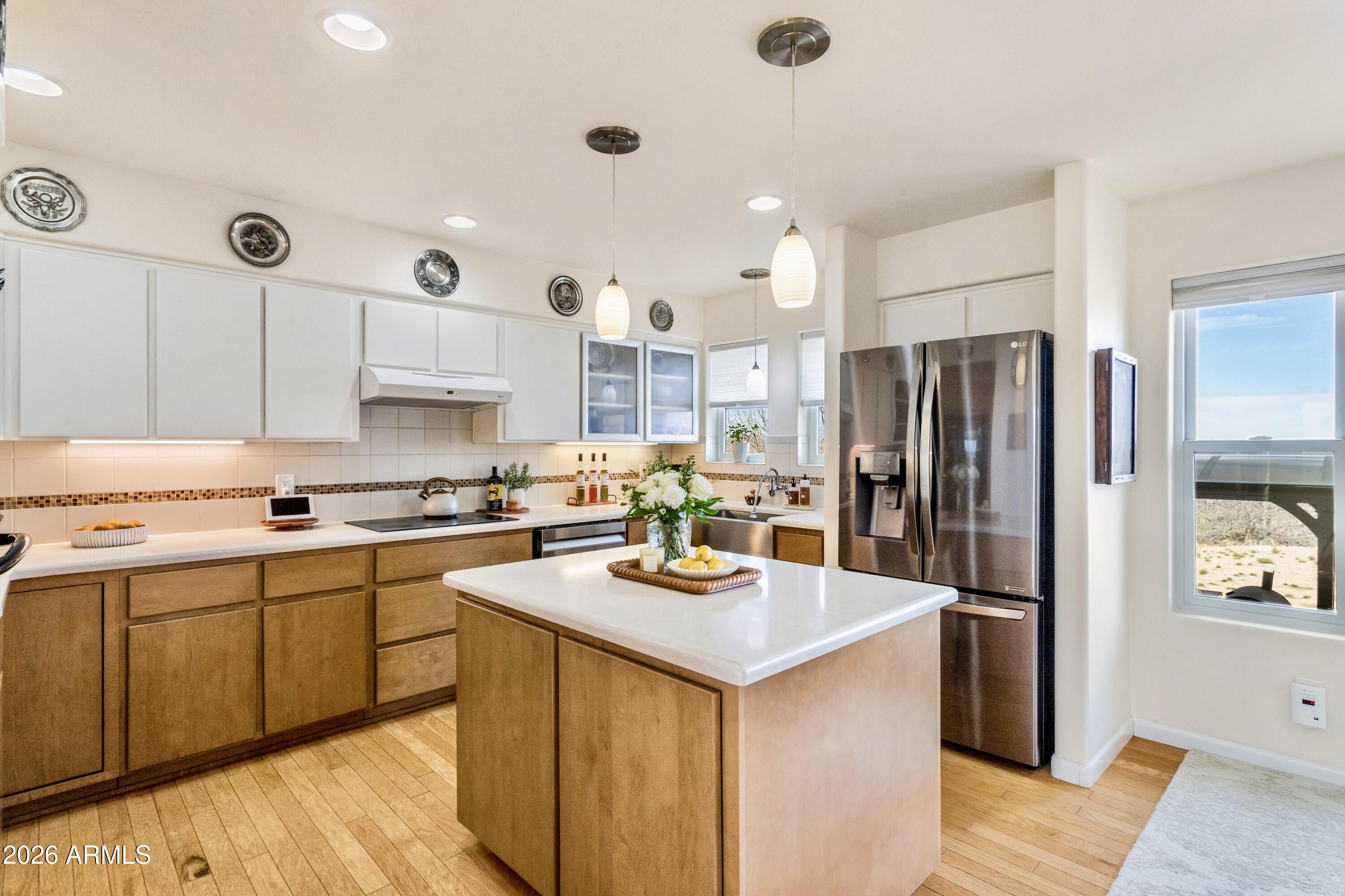 8541 South Almosta Ranch Road Hereford, AZ 85615 - Photo 7 of 53 a kitchen with stainless steel appliances a refrigerator a sink dishwasher a stove and white cabinets with wooden floor