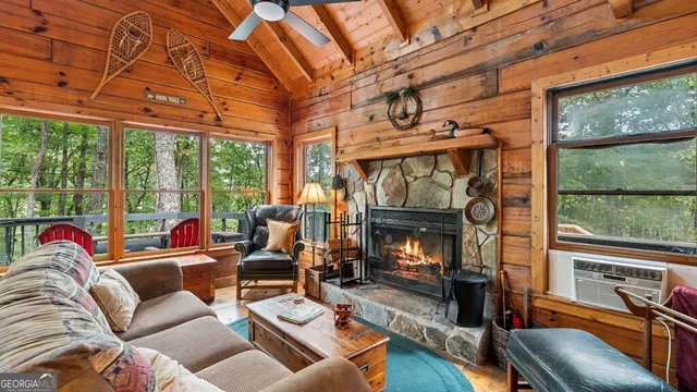 a living room with furniture a fireplace and floor to ceiling windows