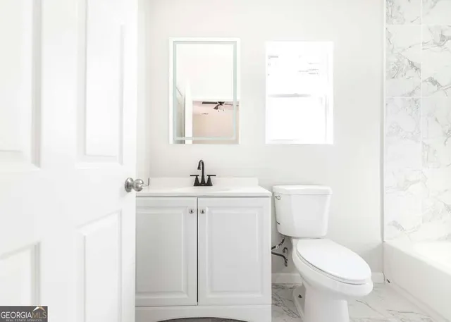 a bathroom with a toilet a sink a mirror and a window