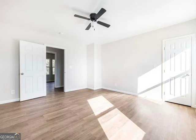 an empty room with wooden floor fan and windows