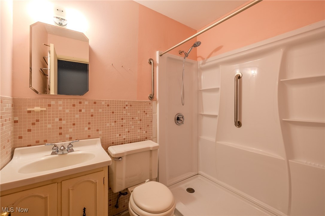 8226 Cedar Road Chesterland, OH 44026 - Photo 40 of 46 Bathroom with tile walls, vanity, a wainscoted wall, and a shower