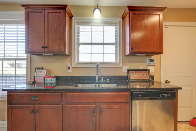 a kitchen with granite countertop cabinets stainless steel appliances a sink and a window