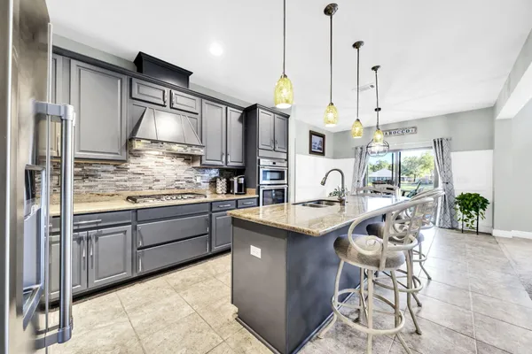 a large kitchen with granite countertop a large kitchen island a sink stainless steel appliances and cabinets