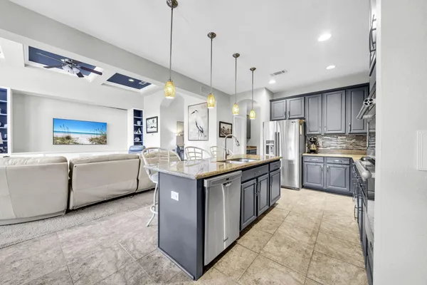 a kitchen with stainless steel appliances granite countertop a stove top oven a refrigerator a sink and a dining table with wooden floor