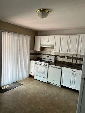 a kitchen with granite countertop white cabinets and white appliances