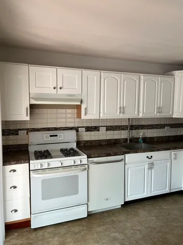 a kitchen with granite countertop white cabinets and white appliances