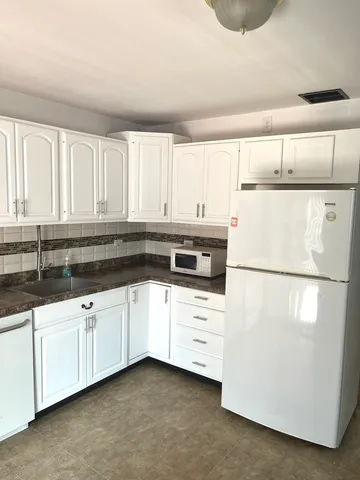 a kitchen with granite countertop white cabinets and white appliances