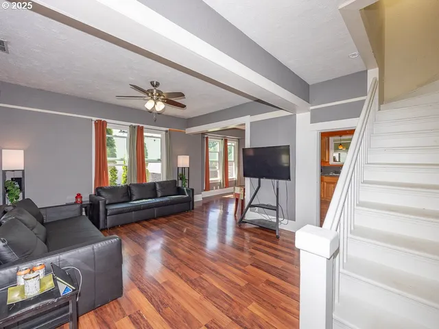 a living room with furniture a flat screen tv and a floor to ceiling window
