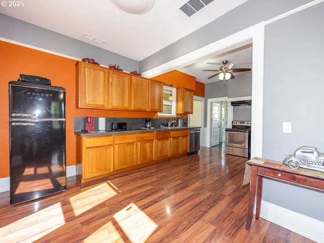 a kitchen with stainless steel appliances granite countertop a refrigerator a stove and a wooden floors