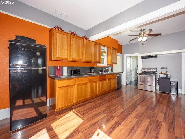 a kitchen with granite countertop a refrigerator a stove top oven and wooden floors