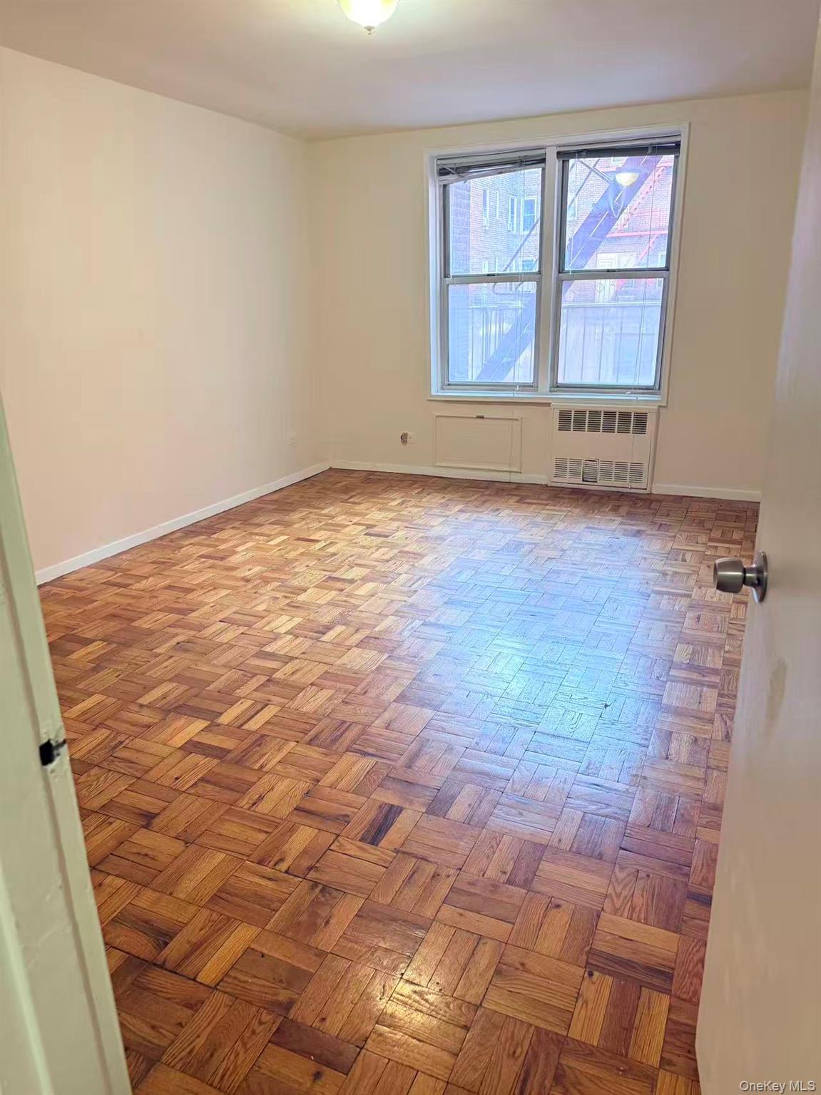 41-07 Bowne Street, Unit 1 Queens, NY 11355 - Photo 2 of 10 an empty room with wooden floor and windows