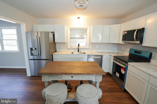a kitchen with a sink a stove a refrigerator and white cabinets