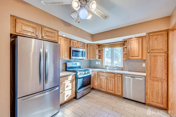 a kitchen with stainless steel appliances granite countertop a refrigerator a sink dishwasher a stove and a refrigerator with wooden floor