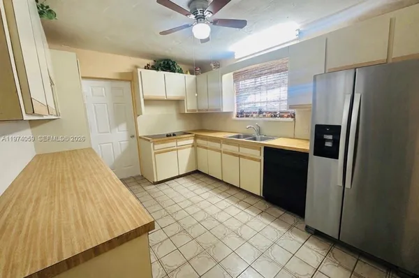 a kitchen with stainless steel appliances a sink a stove a refrigerator cabinets and a window