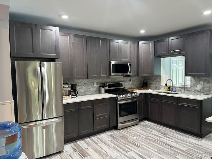 84 Mongaup Road Hurleyville, NY 12747 - Photo 7 of 50 Kitchen featuring dark wood-finish cabinetry, light-toned countertops, a full suite of stainless steel appliances, a tiled backsplash, and recessed lighting