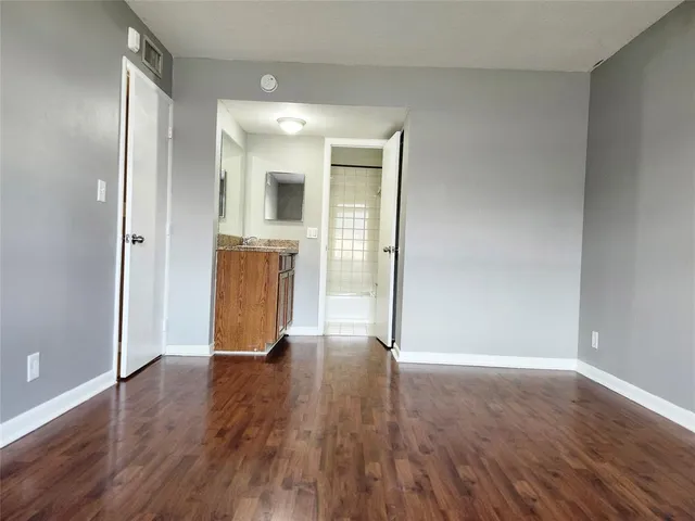 an empty room with wooden floor and bathroom