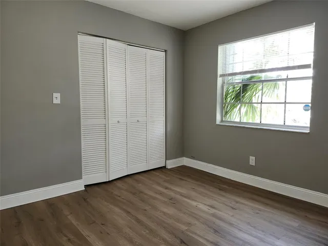 an empty room with wooden floor cabinet and windows
