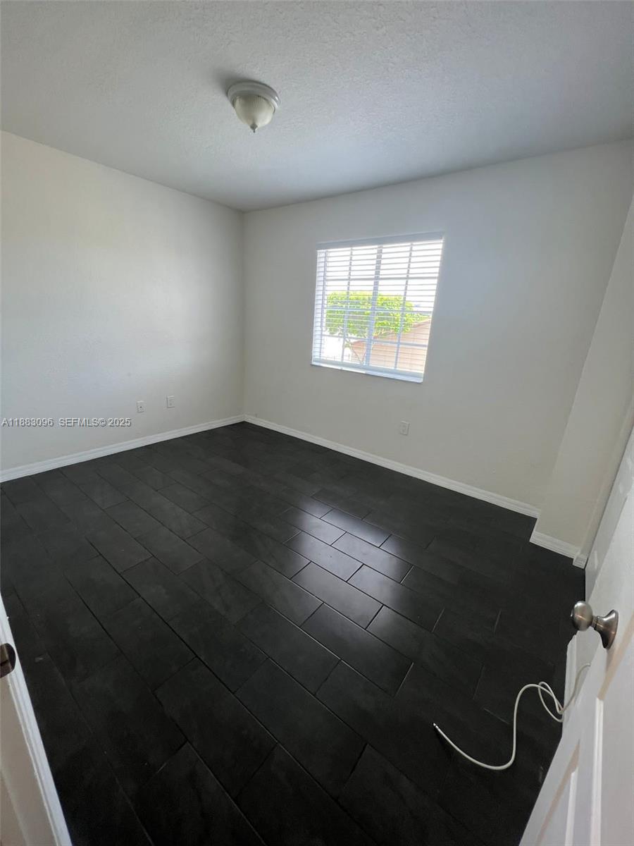 17018 Southwest 138th Court Miami, FL 33177 - Photo 9 of 22 an empty room with wooden floor and windows