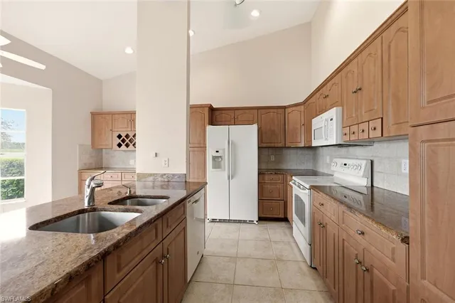 a kitchen with stainless steel appliances granite countertop a sink a refrigerator and a granite counter tops