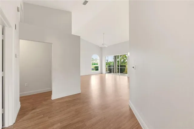 a view of an empty room with a window and wooden floor