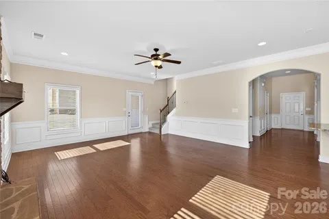 a view of an empty room with wooden floor and a ceiling fan