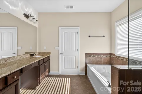 a bathroom with a granite countertop tub a sink and a window