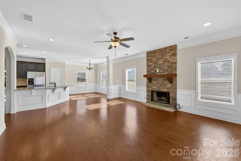 a view of a livingroom with fireplace wooden floor and a kitchen