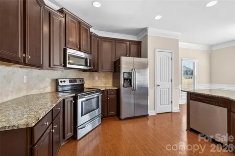a kitchen with granite countertop wooden cabinets a refrigerator and a sink