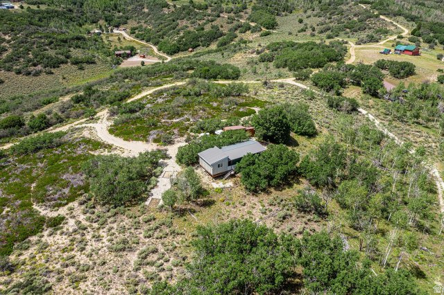 1840 East Ridge Road, Unit 177 Salina, UT 84654 - Photo 21 of 26 Hillside property featuring a single-story residence with a dark-pitched roof and light-colored siding, surrounded by mature trees and natural vegetation