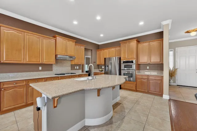 a kitchen with stainless steel appliances granite countertop a sink refrigerator and cabinets