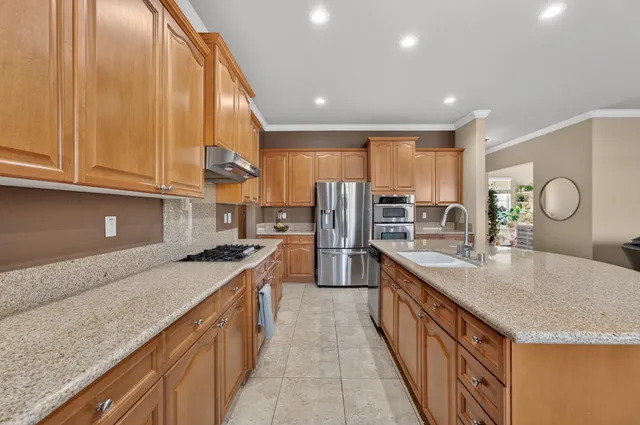 a kitchen with stainless steel appliances granite countertop a sink a stove and a wooden cabinets
