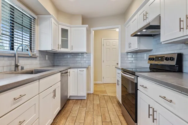 a kitchen with stainless steel appliances granite countertop white cabinets and a counter top space