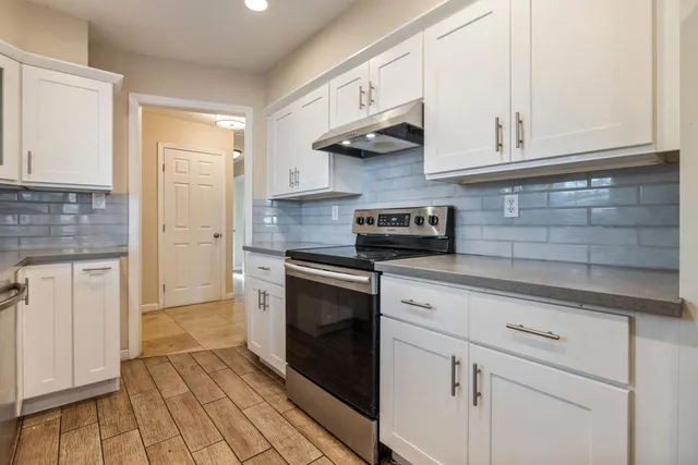 a kitchen with granite countertop white cabinets and stainless steel appliances
